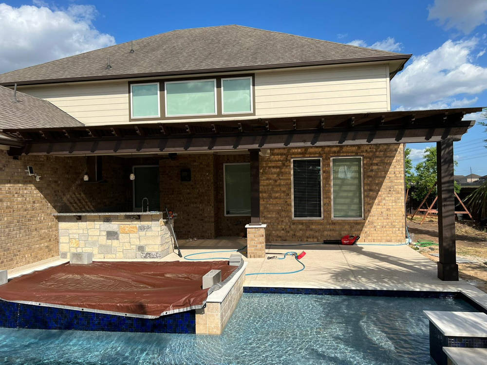 Attached solid-roof patio cover providing shade for a Katy backyard